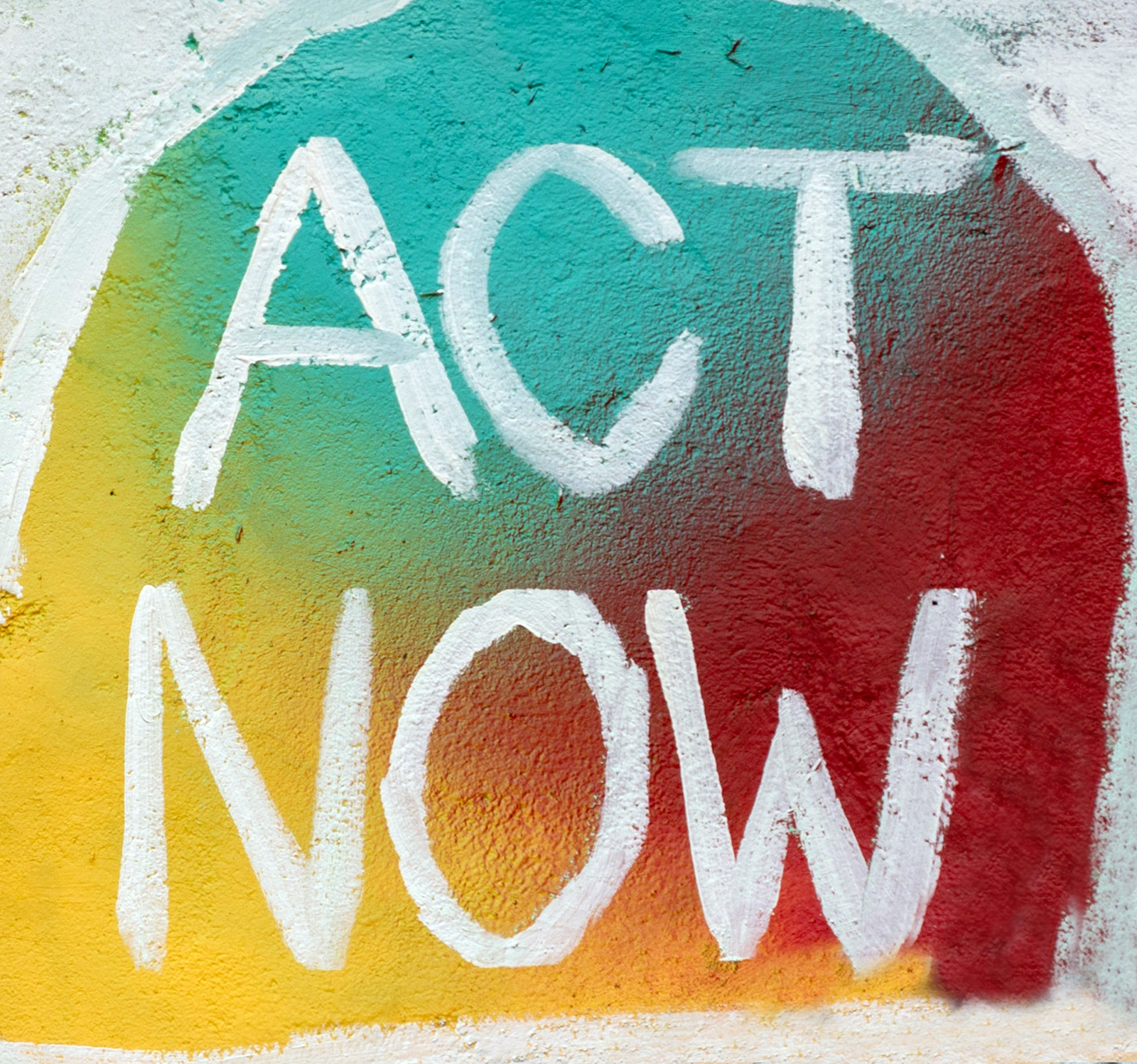 Sign of colorful mural with white text that says Act Now